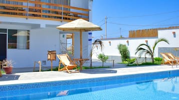 Una piscina al aire libre, sombrillas, sillones reclinables de piscina