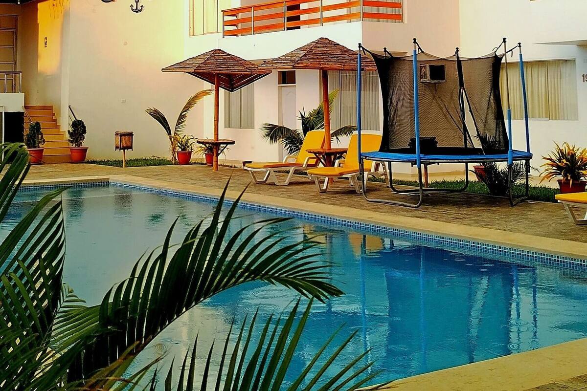 A hotel with a swimming pool, outdoor seating, and a balcony with a view of the pool.