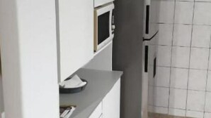 Una cocina con armarios blancos, un refrigerador gris y un rebozado de azulejos.