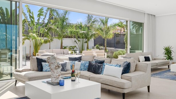 A modern living room with a large sofa, a coffee table, and a view of a tropical garden through large windows. - KARAT Villa Splendida (Playa Paraiso)