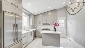 Una cocina moderna con una isla central, electrodomésticos de acero inoxidable y armarios de color gris claro.
