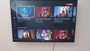Een flatscreen televisie bevestigd aan een muur boven een houten tv-meubel, met een aansluitpunt voor kabels.
