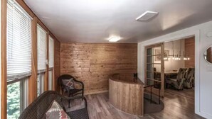 Une pièce aux murs en bois, avec un comptoir d’accueil incurvé et un espace détente comprenant une chaise et un canapé.