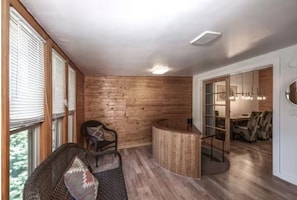 A room with wooden walls, a curved reception desk, and a seating area with a chair and a sofa. - Alto Gem - Mtn View Rendezvous - Hot Tub - Great Views (Alto)