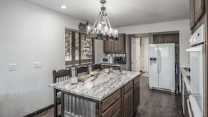 A kitchen with a marble island, wooden cabinets, a built-in microwave, and a refrigerator. - Bearadise - Upper Canyon Gem, Hot Tub, Game Room, HUGE deck (Ruidoso)