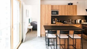 Une cuisine moderne avec des meubles en bois, un plan de travail noir et un coin repas équipé de quatre chaises.