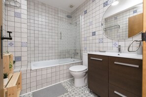 Un baño con bañera, inodoro y armarios de madera.