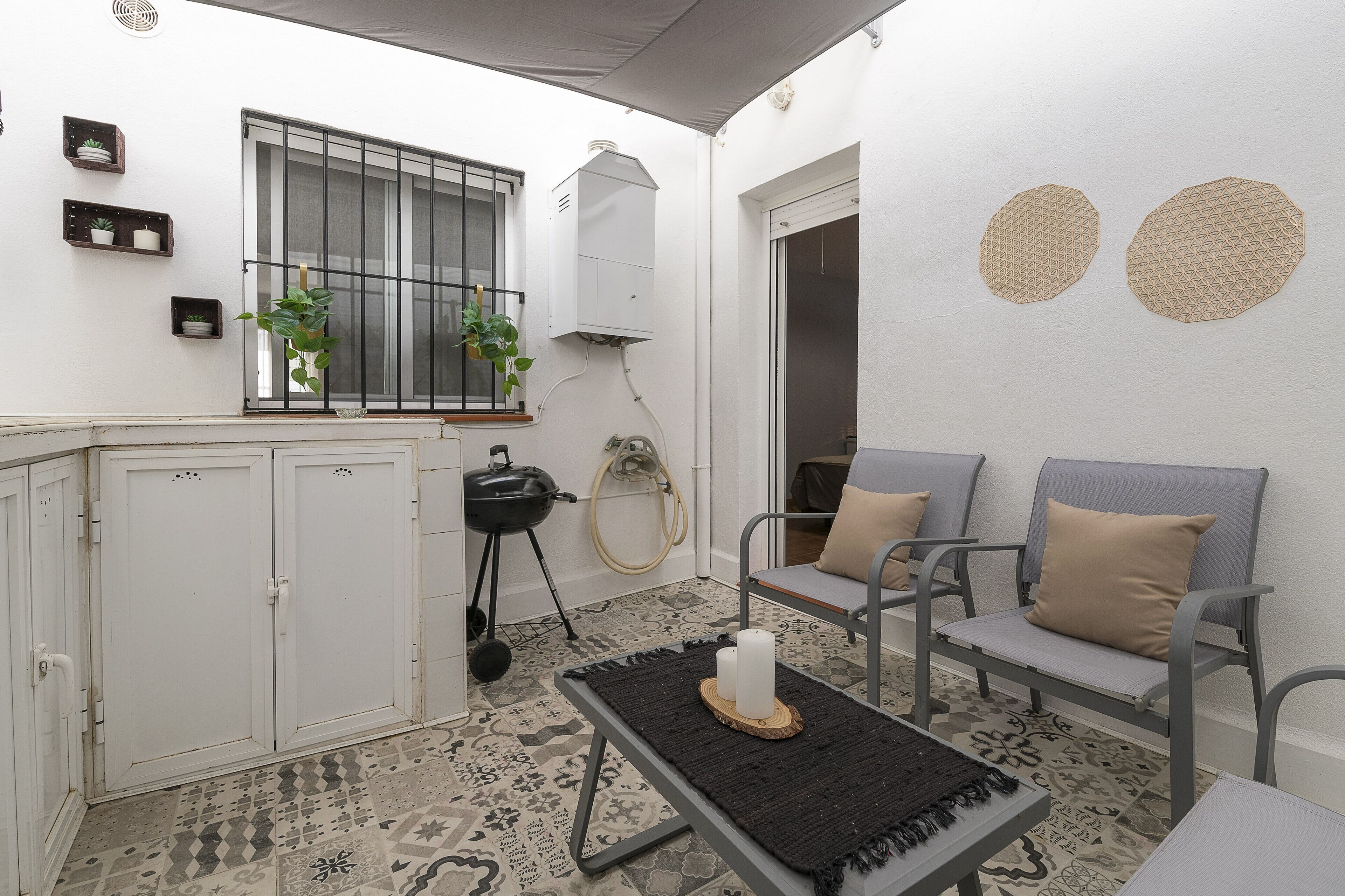 Ein kleiner, sauberer Raum mit Fenster, Wasserkocher, Grill und einer Sitzecke mit zwei Stühlen und einem Tisch.