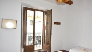 A room with a large sliding glass door leading to a balcony, a small bedside table with a book, and a framed picture on the wall. - Charming town house in the center of Roses, Costa Brava! Two rooms, 200 meters from the beach. Modern kitchen and balcony with sea views. (Roses)