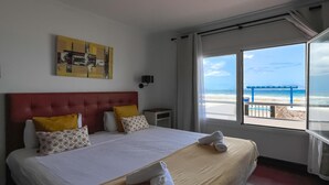 Ein Hotelzimmer mit Bett, Fenster mit Meerblick und einem Bild an der Wand.
