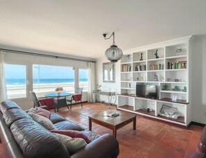 Ein Wohnzimmer mit einer Couch, einem Couchtisch, einem Fernseher und einem Bücherregal.