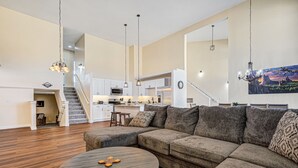 A spacious living room with a large sectional sofa, a round coffee table, and a staircase leading to an upper level. - Spacious Luxury and Mountain Views (Colorado Springs)