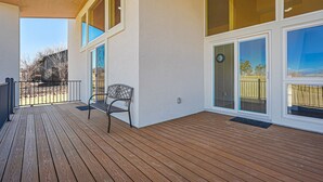 A covered wooden deck with a bench, large windows, and a view of the outdoors. - Spacious Luxury and Mountain Views (Colorado Springs)