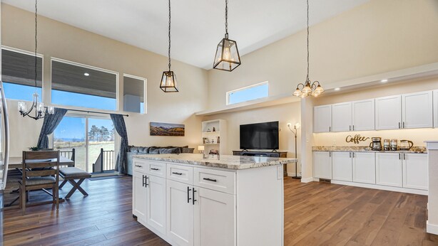 A spacious kitchen with white cabinets, a large island, and a dining area with a view. - Spacious Luxury and Mountain Views (Colorado Springs)