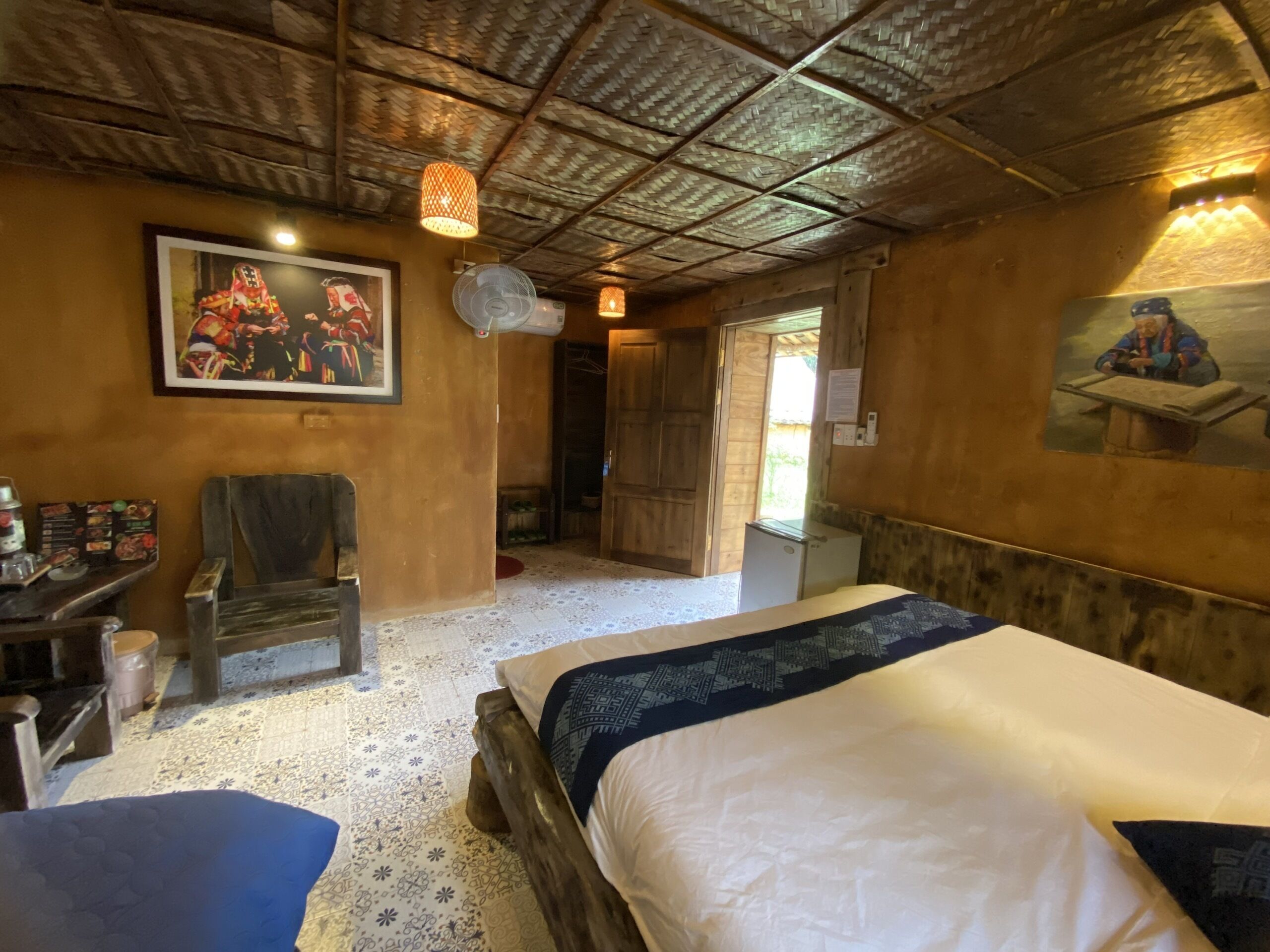 A room with a bed, a chair, a desk, and a wall-mounted picture.