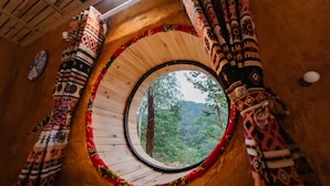 Una ventana circular con vistas a una zona boscosa.