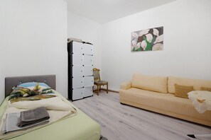 A room with a bed, a sofa, a chair, a wardrobe, and a painting on the wall. - Holiday Apartment "An der Mosel" with Wi-Fi (Kaisersesch)