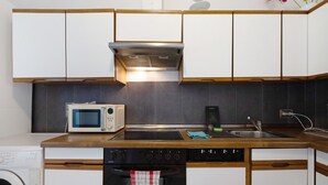 Une cuisine compacte équipée d’un four à micro-ondes, d’une cuisinière, d’un four et d’un petit évier.