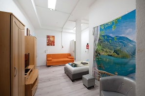 A room with a bed, a sofa, a wooden wardrobe, and a large window with a mountain view. - Holiday Apartment "An der Mosel" with Wi-Fi (Kaisersesch)
