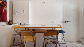 Une pièce avec une table en bois, deux chaises, une armoire blanche et une porte dotée d’une poignée.