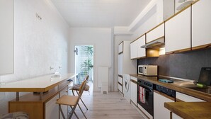 Une cuisine de taille réduite, équipée d’un four à micro-ondes, d’un four traditionnel et de meubles de rangement en bois.