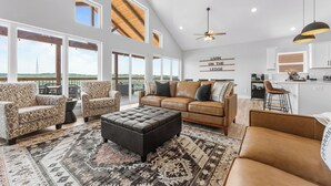 A spacious living room with a large window, a sofa, a coffee table, and a rug.
