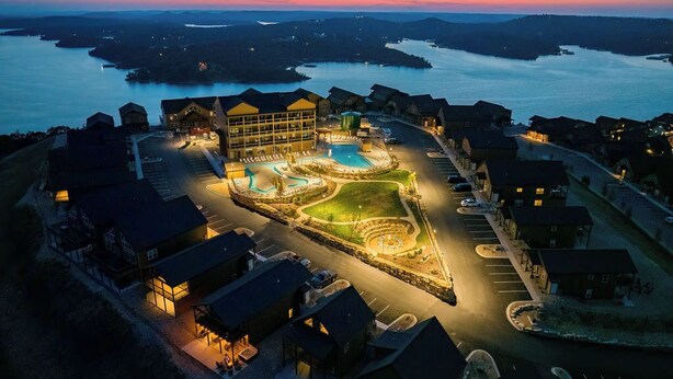 An aerial view of a resort with a swimming pool, multiple buildings, and a waterfront.