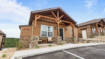 A two-story building with a wooden exterior, stone accents, and a covered porch with seating.
