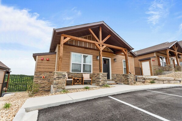 A two-story building with a wooden exterior, stone accents, and a covered porch with seating.