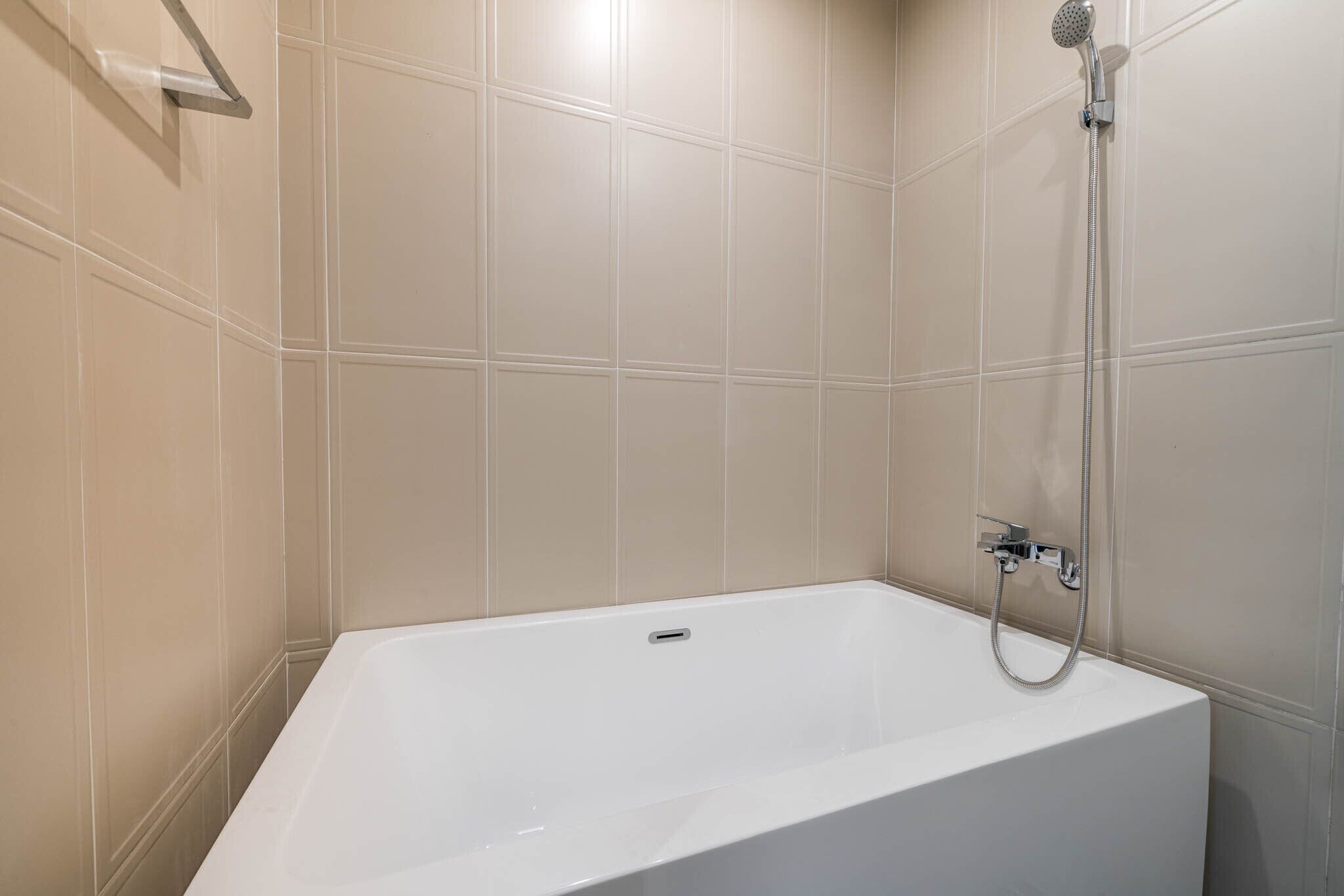 A modern bathroom with a freestanding bathtub, a handheld showerhead, and a wall-mounted towel rack.