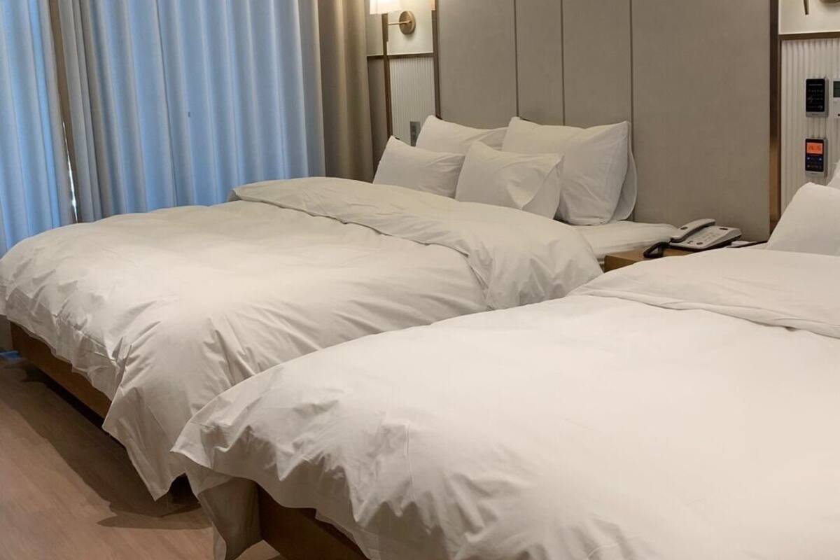 A hotel room with two beds, a bedside phone, and a lamp on the nightstand.