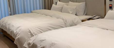 A hotel room with two beds, a bedside phone, and a lamp on the nightstand.