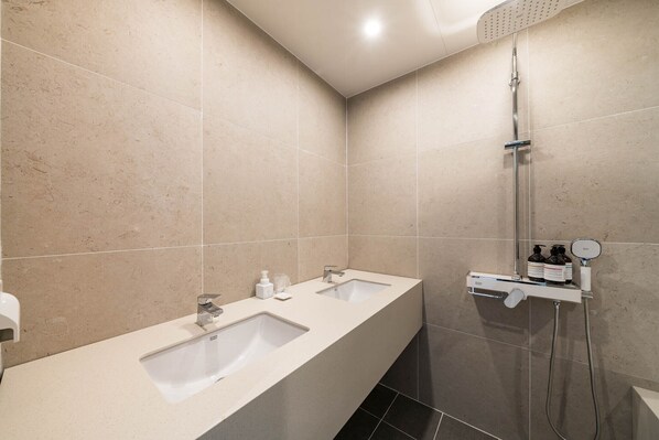 A modern bathroom with two sinks, a shower, and a mirror.