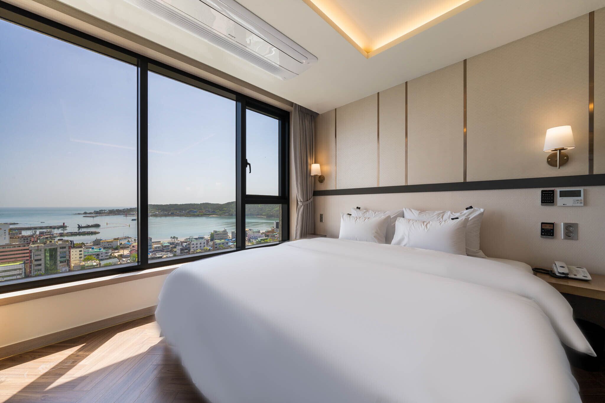 A hotel room with a large bed, a view of the sea, and a modern design.