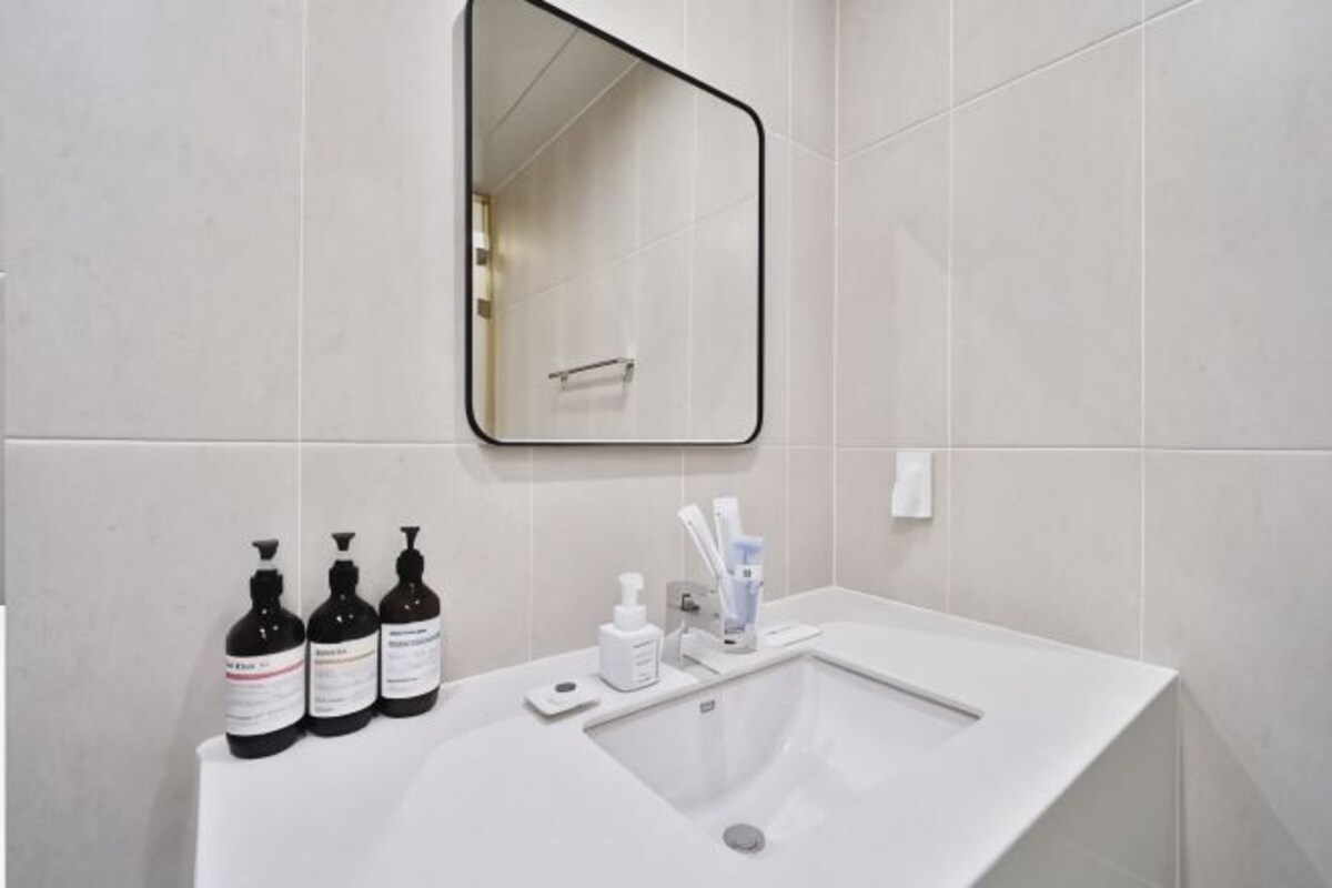 A bathroom with a white sink, a mirror, and toiletries on the counter.