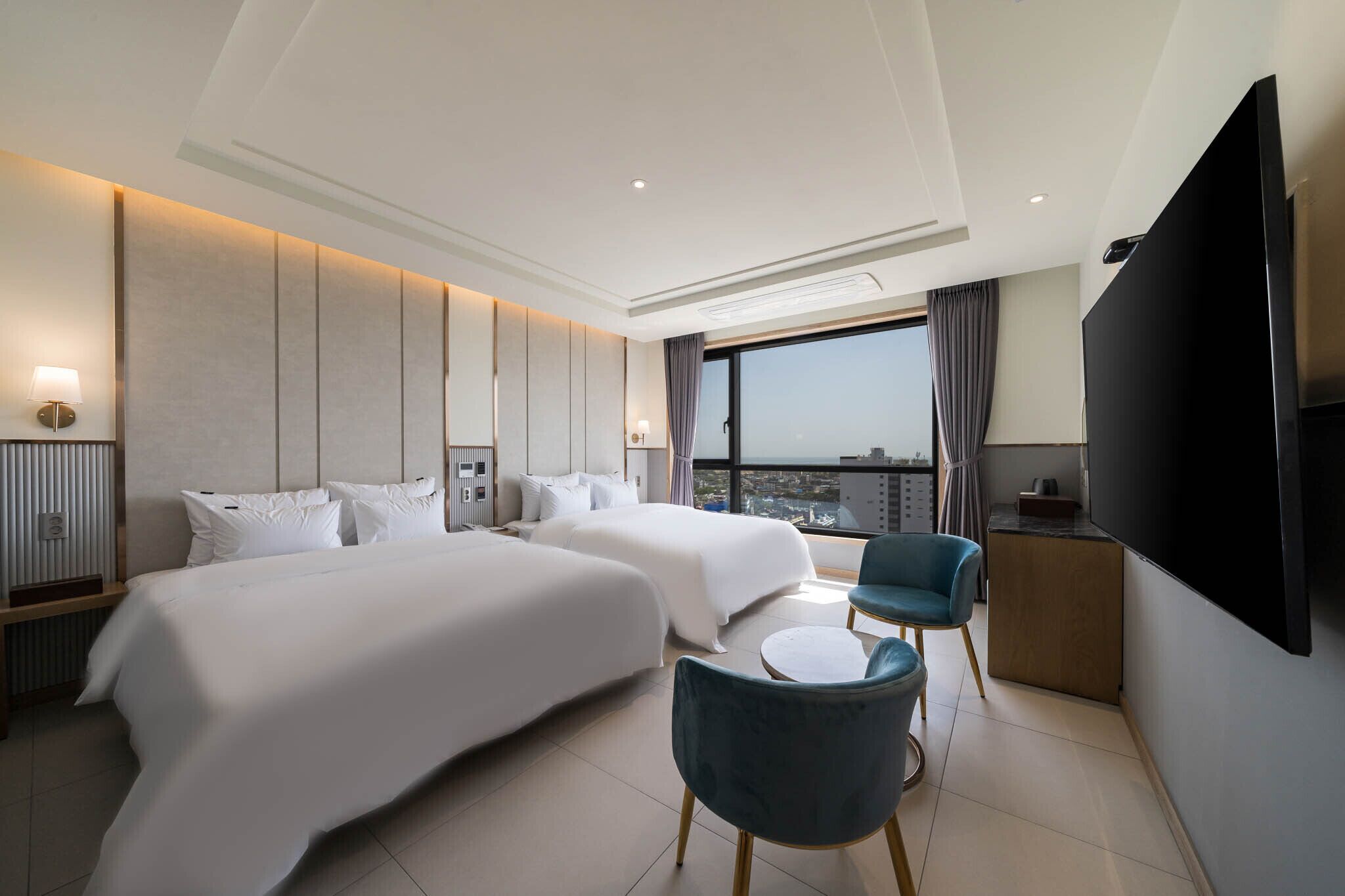 A hotel room with two beds, a TV, a desk, and a chair.