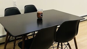 Ein Konferenztisch mit vier Stühlen, ein kleiner Blumentopf an der Fensterbank und eine Kaffeeglasur auf dem Tisch.