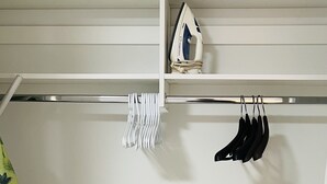 Ein Kleiderschrank mit Kleiderstange, einem Regal mit einem kleinen Gegenstand und einem schwarzen zylindrischen Objekt auf dem Boden.