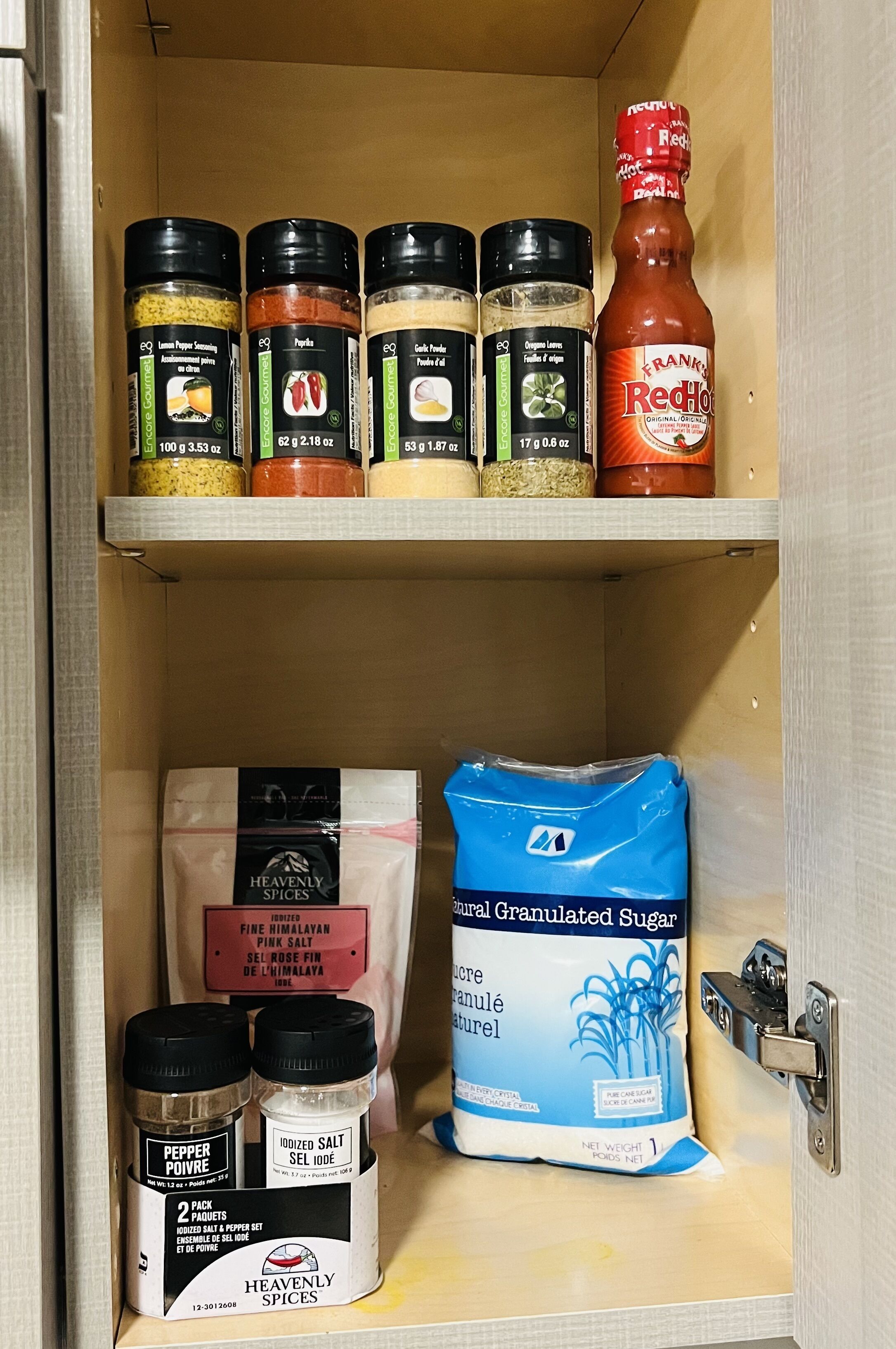 A pantry with various spices and condiments, including pepper, iodized salt, and granulated sugar.