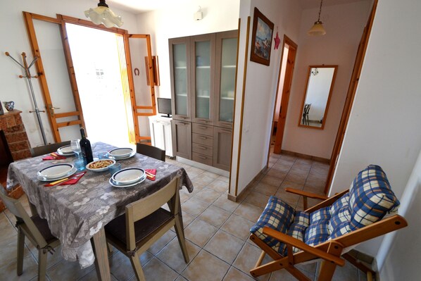 A dining area with a table set for four, a wooden chair, a cabinet, and a mirror.