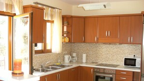 Une cuisine avec des meubles de rangement en bois, un évier, une cuisinière et un four à micro-ondes.