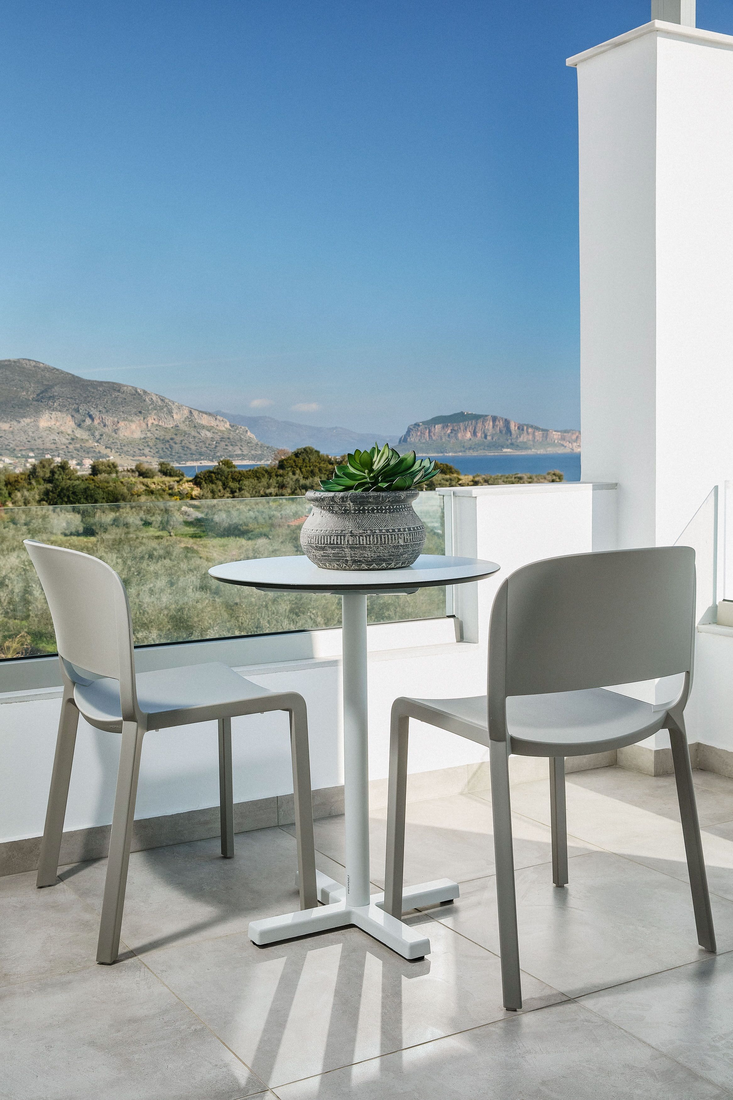 A balcony with two chairs, a table, and a potted plant.