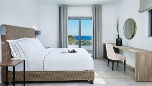 Une chambre d’hôtel moderne avec un grand lit, un bureau et une vue sur l’océan.