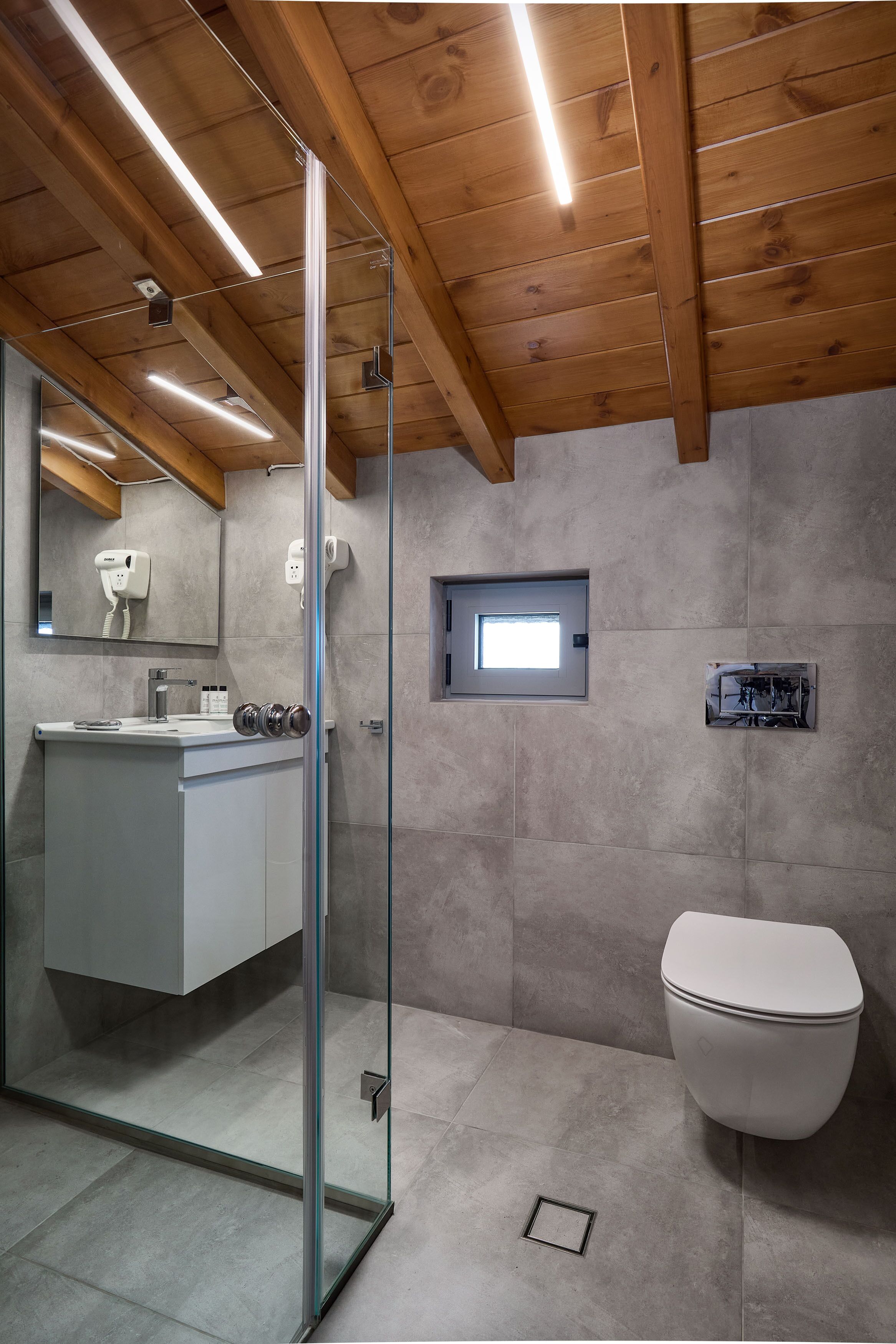 Un baño moderno con cabina de ducha de vidrio, un inodoro blanco y un lavabo con espejo.