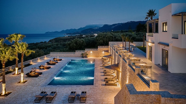 Un espace aménagé au bord de la piscine, avec des chaises longues et une vue sur la mer et les montagnes.