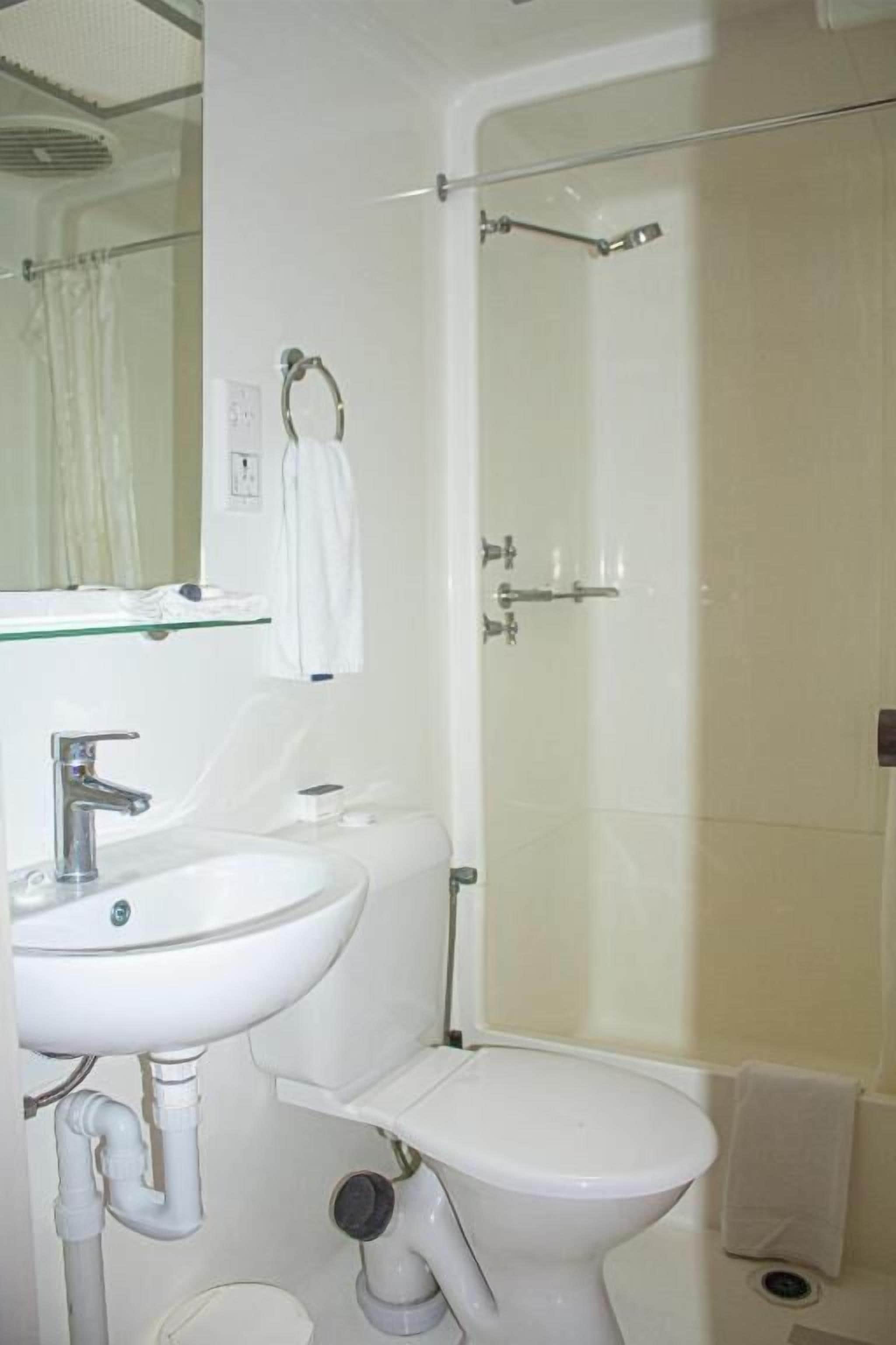 A bathroom with a white sink, toilet, and glass shower enclosure.