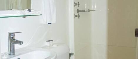 A bathroom with a white sink, toilet, and glass shower enclosure.