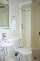 A bathroom with a white sink, toilet, and glass shower enclosure.