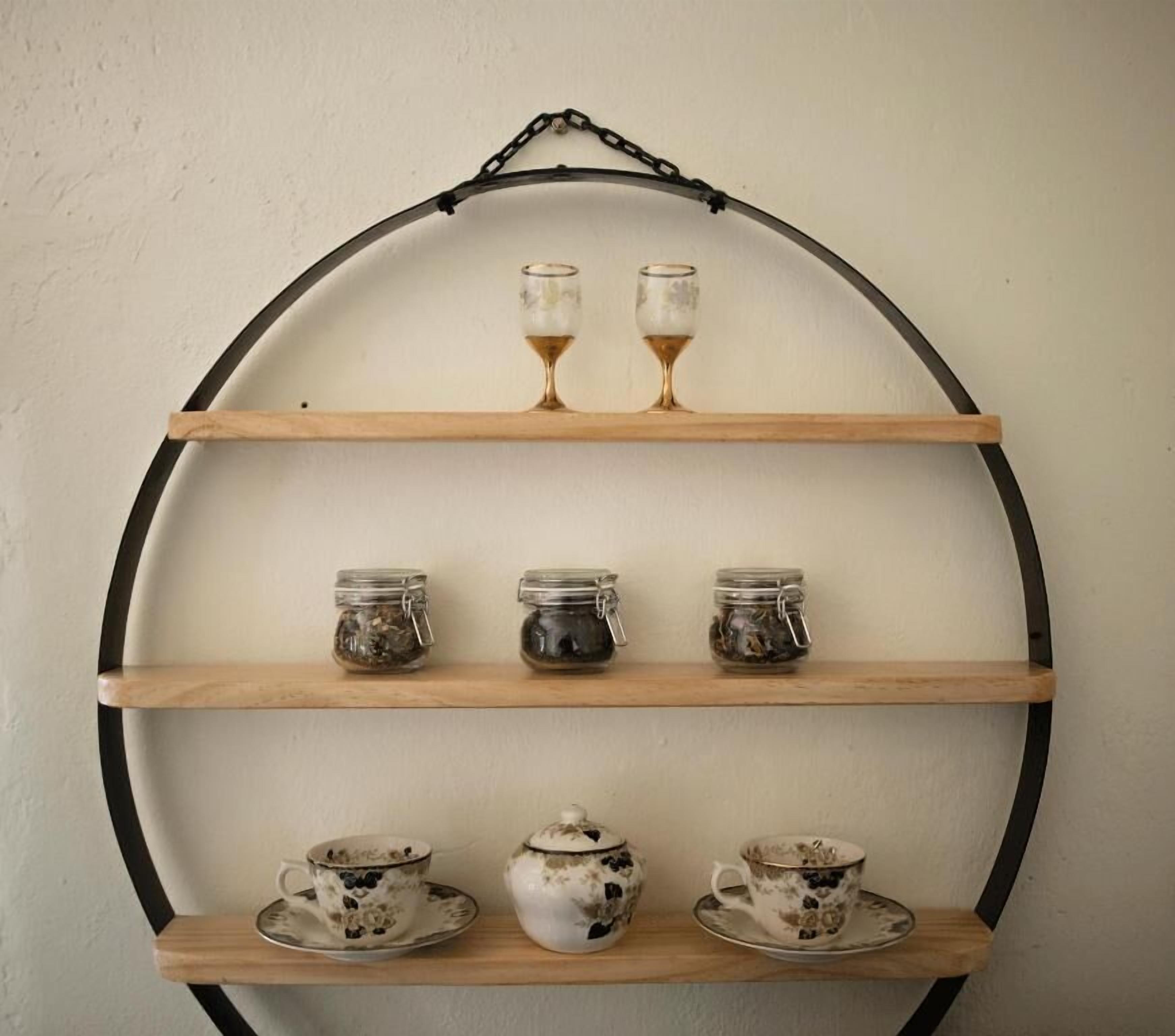 A wall-mounted shelf with three tiers, each holding different items.