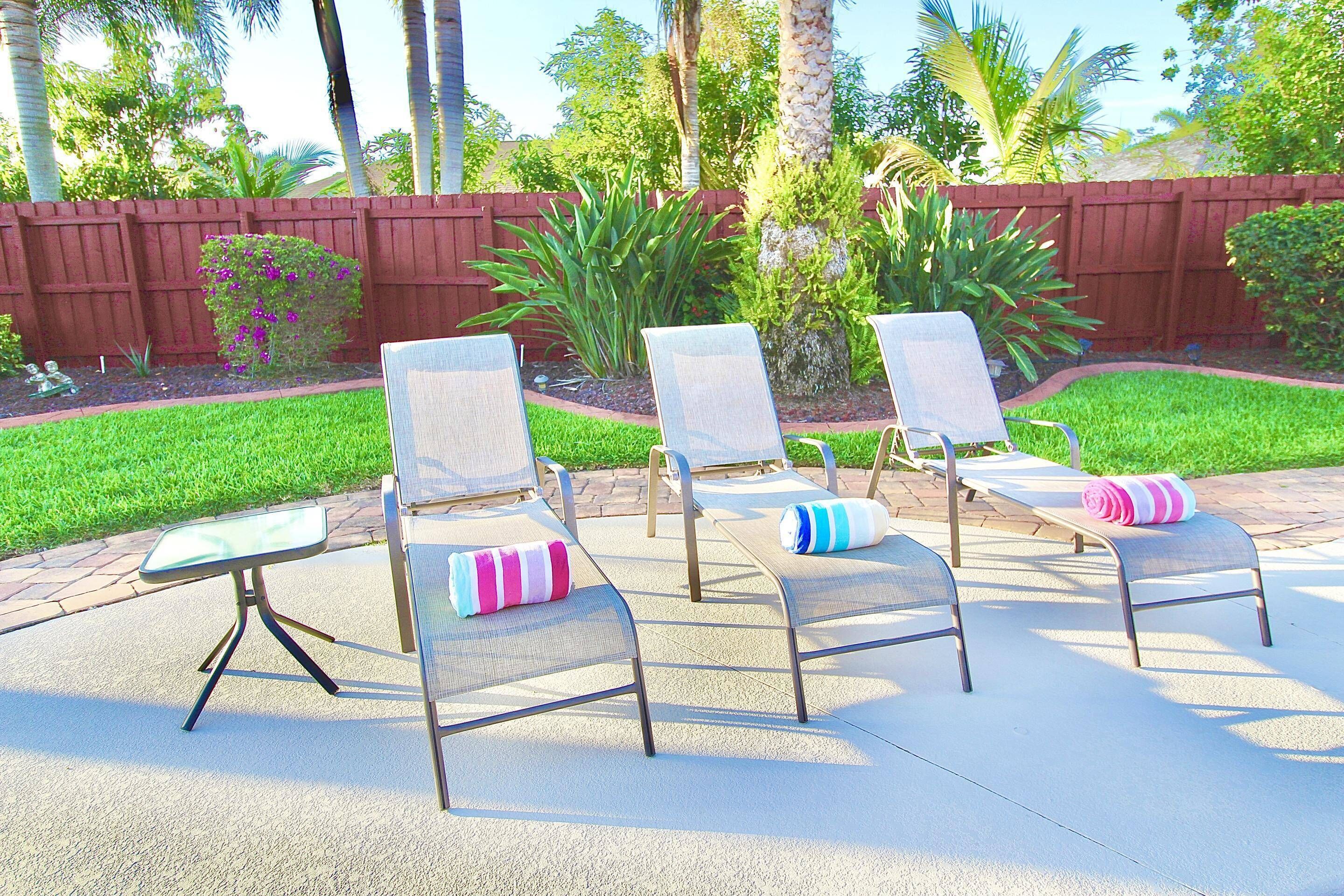 A patio with four lounge chairs, each with a pillow.